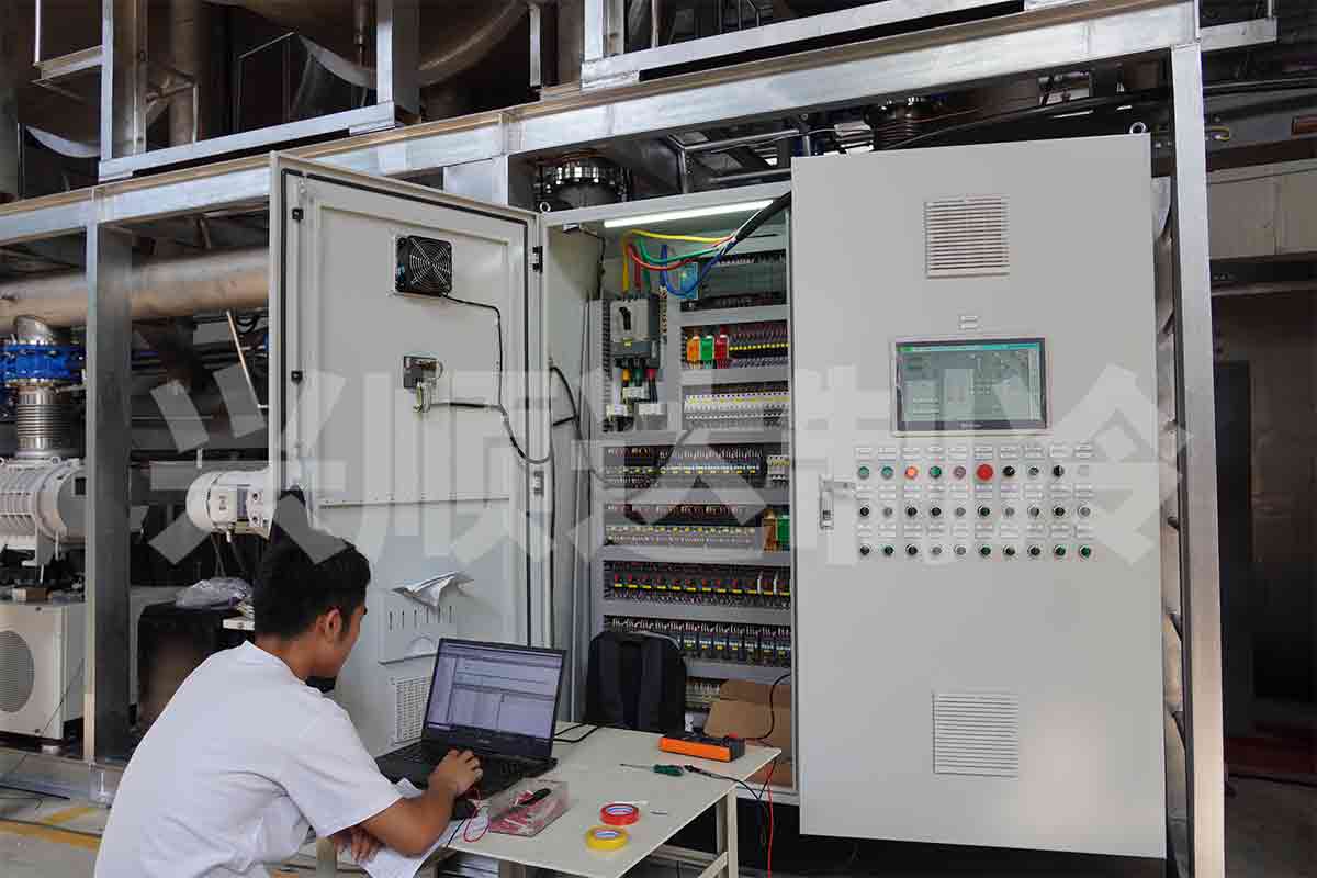Technician testing a commercial food freeze dryer control system during factory inspection